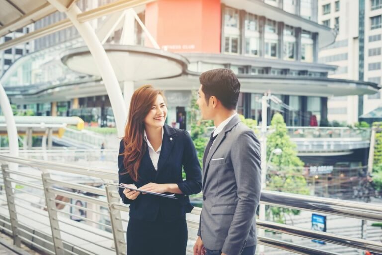 homme-affaires-qui-pointe-document-sourire-discute-quelque-chose-son-collegue-debout-devant-bureau_1150-2440